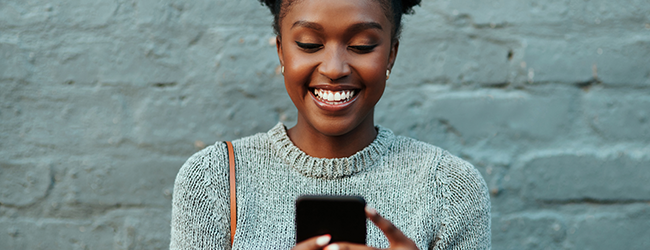 A young woman smiling at her phone