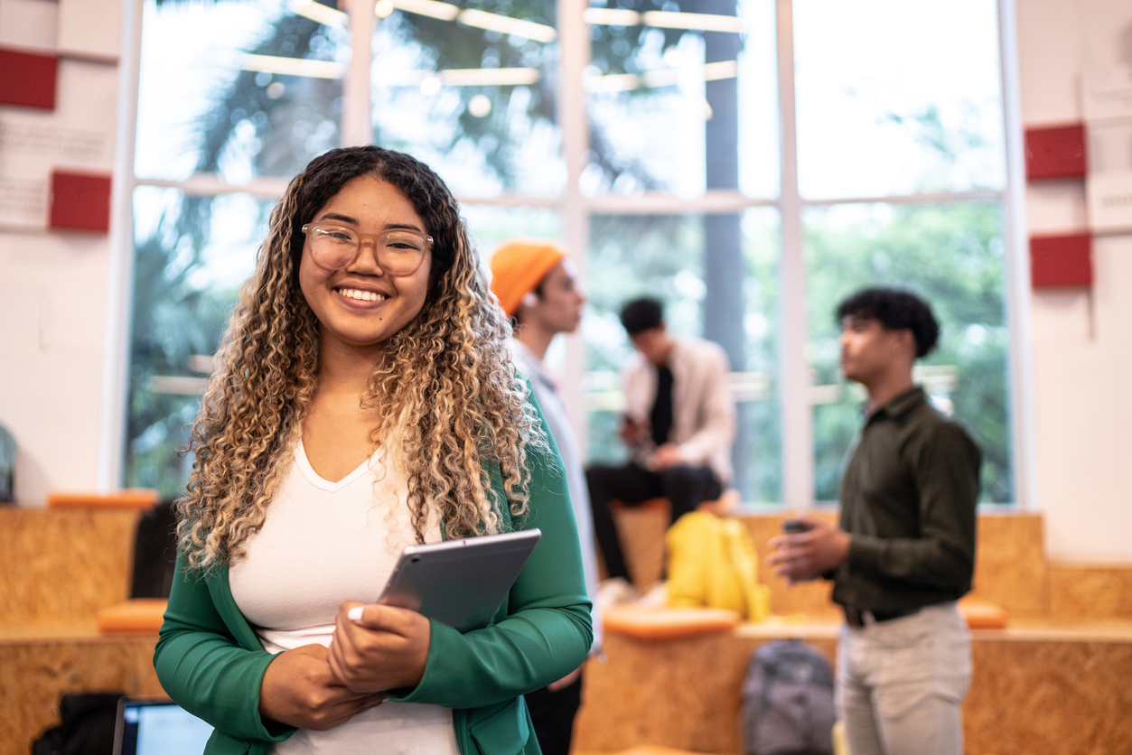 Portrait of a young student woman holding a digital tablet at university auditorium